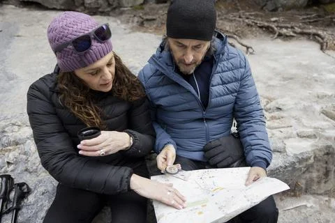 Couple sitting looking at map on rock Fotos Stock
