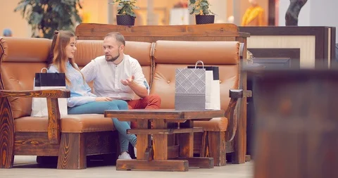 Couple sitting in the mall on the couch and talking about something Stock Footage 95963358