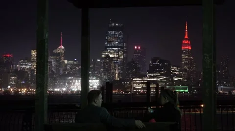A couple sitting opposite of upper Manhattan. Night city lights Stock Footage 66569246
