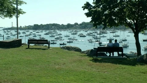 A Couple Sitting On a Park Bench Overlooking a Bay with Sail Boats  库存影片 79606809