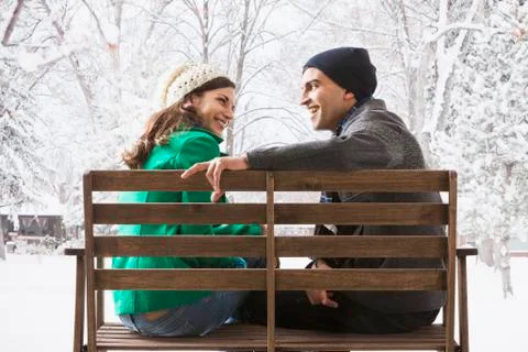 Couple sitting on park bench in snow Stock Photos