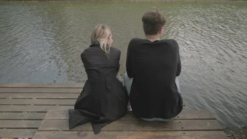 Couple sitting on the pier and talking Stock Footage 136652456