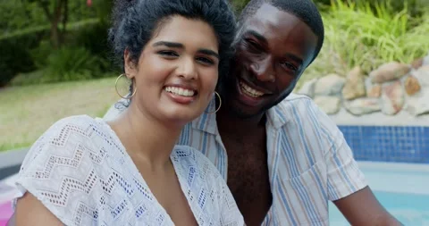 Couple sitting poolside, wearing crochet coverup and striped shirt, meeting Stock Footage 340987533