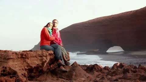 Couple sitting on rocks on beautiful Legzira beach Stock-Footage 10892553