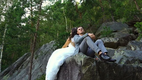 Couple sitting on rocks with forest in background. Slow motion Stock Footage 95857126