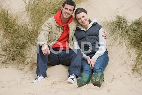 Couple Sitting On A Sand Dune