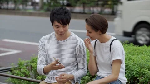 A couple sitting by the side of the road and having a conversation Stock Footage 147600915