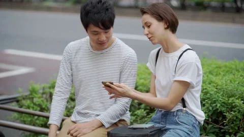 A couple sitting by the side of the road and having a conversation Stock Footage 147600964
