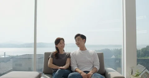 Couple is sitting side by side on the couch and looking at the camera Stock Footage 100941927