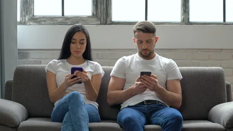 Couple sitting on the sofa and looking in the smartphones. Communication problem Stock Footage 105352332
