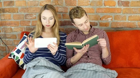 Couple sitting on the sofa and relaxing in different ways, steadycam shot Stock Footage 70849534