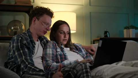Couple sitting on the sofa and watching something on the laptop Stock Footage 166098295