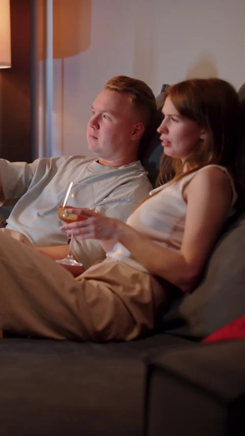 Couple sitting on sofa drinking wine together Vídeos de archivo 323294740