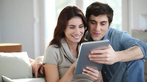 Couple sitting in sofa with electronic pad Stock Footage 14832220