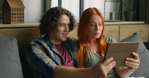 Couple sitting on sofa, having a video chat via tablet computer, close up Stock-Footage 114598192