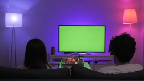 Couple sitting on sofa in lounge designed green screen on television Stock-Footage 130972497
