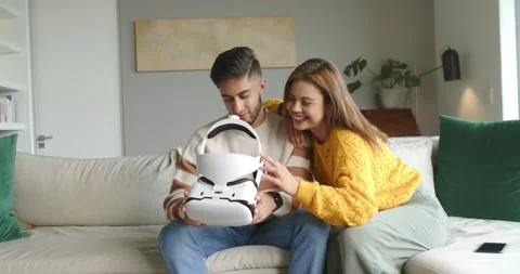 Couple sitting on sofa, man holding VR headset as woman moving in leaning and Stock Footage 337886239