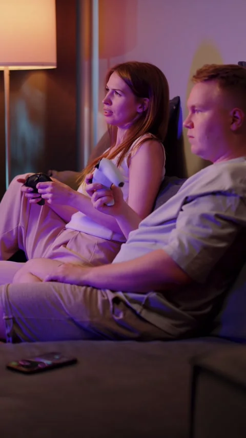 Couple sitting on sofa playing video game 스톡 동영상 323294573