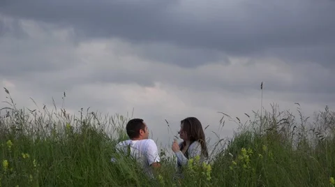 Couple sitting on spring meadow close sky, have fun, smiling, enjoy flower 4K Video stock 46206298