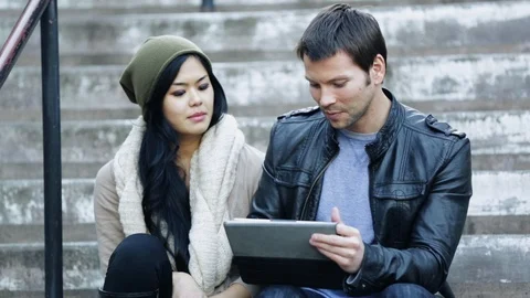 Couple sitting on steps using electronic tablet Stock Footage 120949174