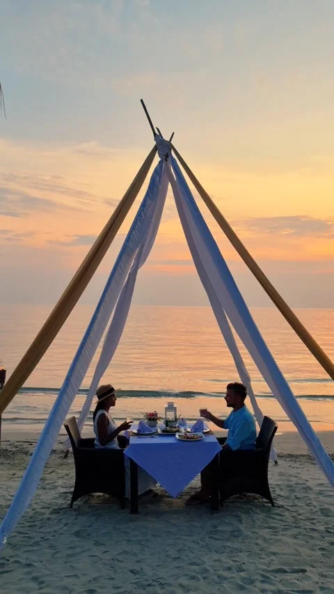 A couple is sitting at a table on the beach under a canopy Stock Footage 267381312