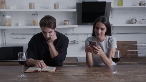 A couple is sitting at a table in their kitchen, a girl is looking at a Vidéo 129370745