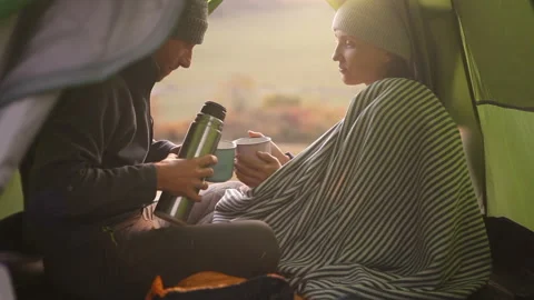 Couple sitting in tent drinking tea from thermos in cold weather Stock-Footage 131331444