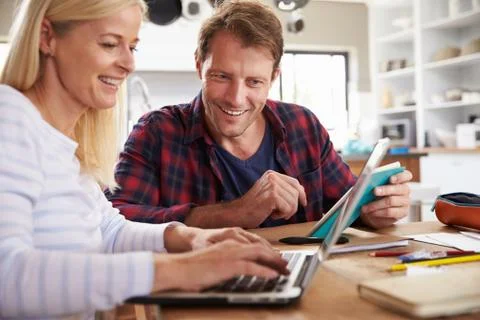 Couple sitting in their kitchen using laptop Foto stock
