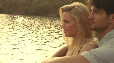 Couple sitting together on dock beside lake. Stock Footage