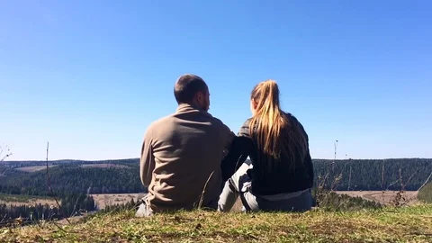 The couple is sitting on top of a mountain and looking at the landscape Stock Footage 75951014