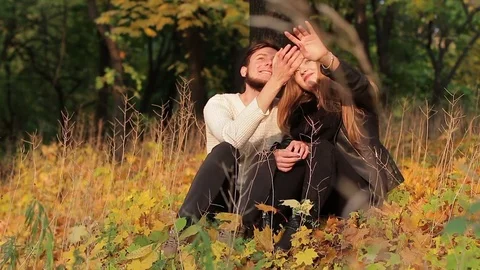 Couple sitting under a tree in an autumn forest or park Video stock 81233980