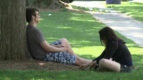 A couple sitting under a tree in the park. Stock-Footage 8693930