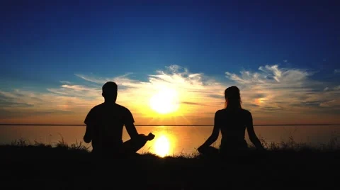 Couple sitting yoga on beach while sunset Stock Footage 68734111