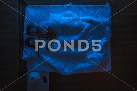 The couple sleeping on a bed. Evening night time. View from above Stock Photos