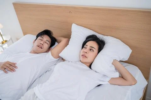 Couple sleeping in bed while one partner looks thoughtfully towards the cei.. Stock Photos