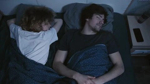 The couple sleeps in bed, the alarm clock rings on the phone, the guy wakes up Vidéo 197367246