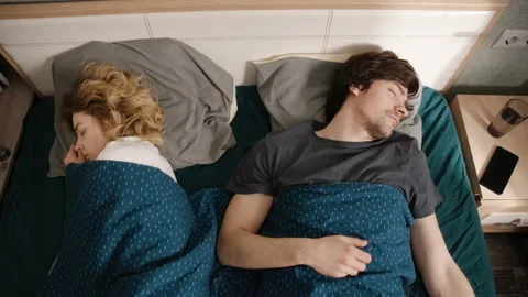 The couple sleeps in bed, the man has an alarm, he turns it off and sleeps on Stock-Footage 197489617