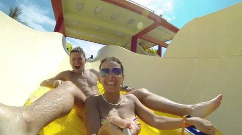 Couple sliding down a water slide at public swimming pool Stock Footage 64146504