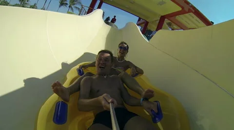 Couple sliding down a water slide at public swimming pool Stock Footage 64147406