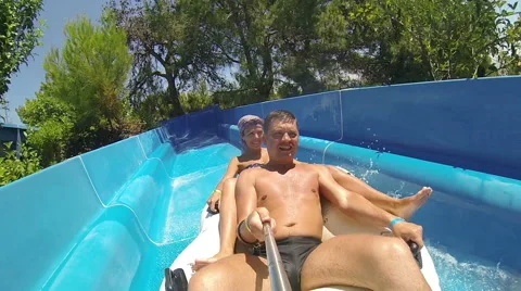 Couple sliding down a water slide at public swimming pool Stock Footage 64150783