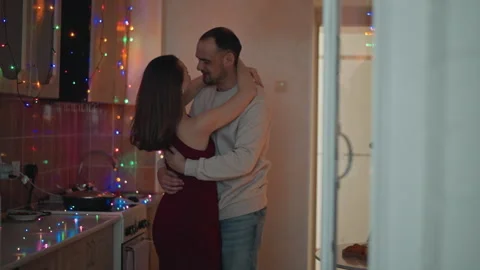 Couple slow dancing in cozy kitchen under multicolor string lights, intimate Stock Footage 346655027