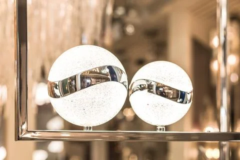 A couple of small round ball-shaped LED lamps on a metal gold frame in a warm Stock Photos