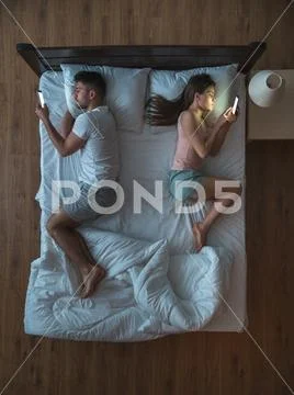 The couple with a smartphone lay on the bed. view from above Stock Photos