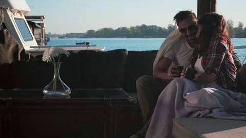 Couple smiling and kissing while holding coffee by the river Stock-Footage 99976829