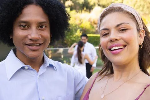 Couple smiling and posing in backyard near pool, wearing light blue shirt, pink Foto stock