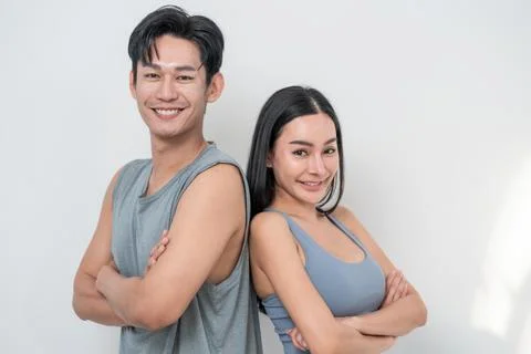 Couple smiling confidently while posing with arms crossed against a light b.. Stock Photos