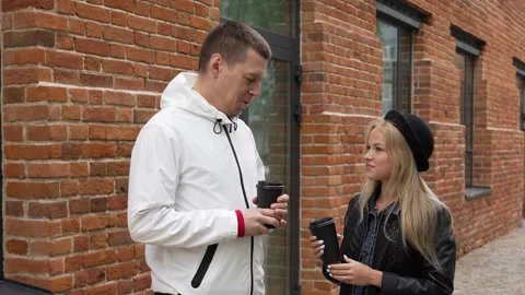 A couple, smiling, drinking coffee outside. A man and a woman are talking on a Stock Footage 266772121