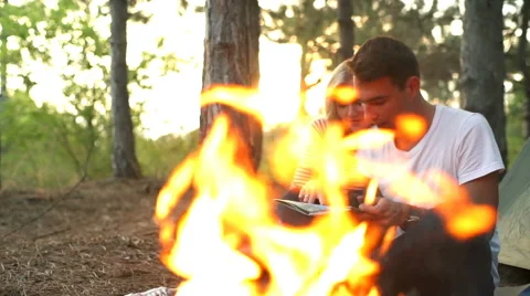 Couple smiling looking for route on map near bonfire in forest Slow motion Video stock 68115787