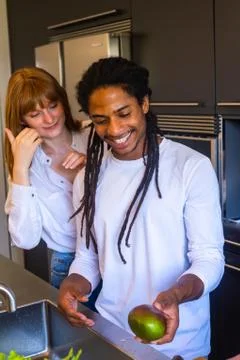 Couple smiling with a mango in the hand in the kitchen Stock Photos