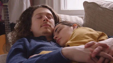 Couple snuggle up on couch to take a nap. Stock Footage 129897997